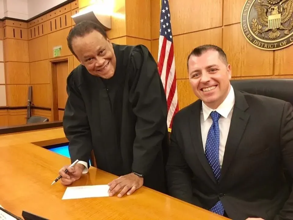 With the Hon. Morrison C. England, Jr., federal clerkship, U.S. District Court, Eastern District of California. Mark C. Smith with the judge during his federal judicial clerkship.