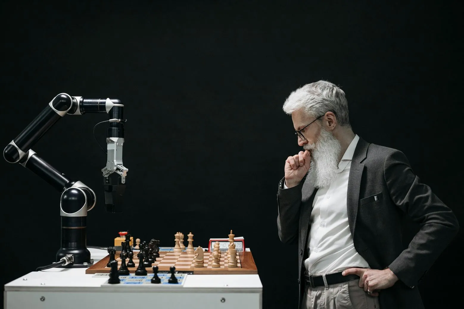 A man playing chess with a robotic arm.
