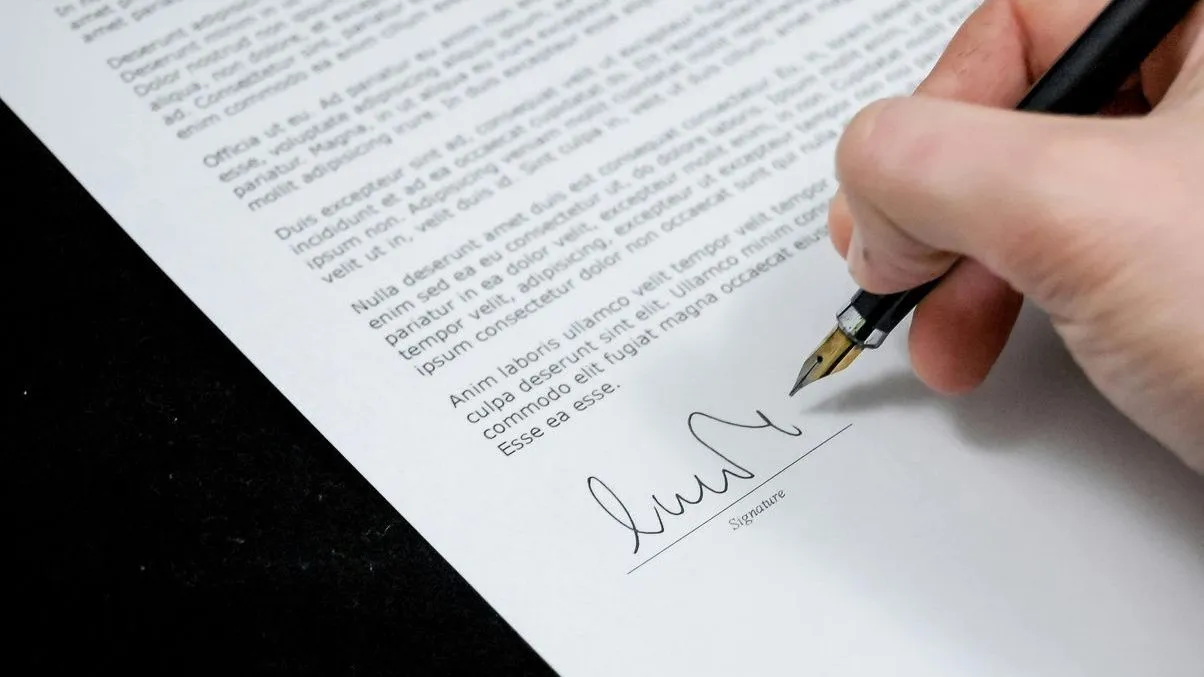 A person signing a document with a fountain pen.